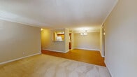 This single-floor residence is thoughtfully designed to maximize both comfort and functionality. The main living area is generously proportioned, featuring warm neutral walls, crown molding, and a combination of plush carpet and hardwood-style flooring. A tile-surround fireplace with a white mantel serves as a focal point, flanked by windows with blinds that allow natural light to filter in. A glass door provides direct outdoor access from the living area, enhancing connectivity to the outside.

The kitchen is laid out in a galley configuration, offering abundant oak cabinetry, light countertops, a double-basin sink, and white appliances including a refrigerator, electric range, built-in microwave, and dishwasher. A pass-through window connects the kitchen to the main living space, adding an open, airy feel to the layout.

The bedrooms are carpeted and each equipped with a ceiling fan and light fixture. One bedroom features a window with blinds that brings in natural light. The bathroom includes warm-toned tile flooring, oak cabinetry with a light countertop, and a full tub-shower combination. Throughout the unit, white trim and baseboards provide a clean, cohesive finish.