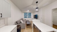 Located at 505 S Fifth St, Unit 202 in Champaign, IL, this one-bedroom, one-bathroom unit offers a thoughtfully designed layout with contemporary finishes throughout. Light wood-look flooring runs seamlessly across the entire space, lending a clean and cohesive aesthetic.

The kitchen is a standout feature, equipped with stainless steel appliances including a full-size refrigerator, electric range, and over-the-range microwave. Gray shaker-style cabinetry with matte black hardware pairs with crisp white countertops and a classic subway tile backsplash. A peninsula with an undermount sink and a modern pendant light above adds both functionality and style, while a dedicated entry door with a keypad lock provides convenient access.

The bedroom is a cozy, well-proportioned room with neutral white walls and light flooring, offering a calm and restful environment. Paneled white doors and simple, clean lines maintain the modern aesthetic carried throughout the unit.

The bathroom continues the same refined palette, featuring a gray vanity with a white countertop, an undermount sink with matte black fixtures, a framed mirror, and warm overhead lighting. Wood-look flooring and crisp white walls complete the space with a fresh, contemporary feel.