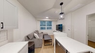 Located at 505 S Fifth St, Unit 202 in Champaign, IL, this one-bedroom, one-bathroom unit offers a thoughtfully designed layout with contemporary finishes throughout. Light wood-look flooring runs seamlessly across the entire space, lending a clean and cohesive aesthetic.

The kitchen is a standout feature, equipped with stainless steel appliances including a full-size refrigerator, electric range, and over-the-range microwave. Gray shaker-style cabinetry with matte black hardware pairs with crisp white countertops and a classic subway tile backsplash. A peninsula with an undermount sink and a modern pendant light above adds both functionality and style, while a dedicated entry door with a keypad lock provides convenient access.

The bedroom is a cozy, well-proportioned room with neutral white walls and light flooring, offering a calm and restful environment. Paneled white doors and simple, clean lines maintain the modern aesthetic carried throughout the unit.

The bathroom continues the same refined palette, featuring a gray vanity with a white countertop, an undermount sink with matte black fixtures, a framed mirror, and warm overhead lighting. Wood-look flooring and crisp white walls complete the space with a fresh, contemporary feel.