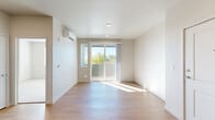 Located at 500 Stoker Ave in Reno, Nevada, this one-bedroom, one-bathroom unit offers a well-designed layout across a single floor. The open-concept kitchen and living area is anchored by light wood-style flooring, recessed lighting, and a wall-mounted mini-split HVAC system. The kitchen features white shaker cabinetry, light countertops, a stainless steel sink, and a full suite of black appliances including a refrigerator, range, over-the-range microwave, and dishwasher. The living area opens directly onto a private balcony through sliding glass doors, filling the space with natural light and outdoor views of the surrounding tree line. The bedroom is carpeted, bathed in natural light from a dedicated window, and is comfortably sized to accommodate standard furnishings. Two closets provide generous storage, including a walk-in closet with wire shelving and hanging rods. The bathroom is finished with wood-style flooring, a light blue vanity with ample drawer storage, a large mirror, built-in open shelving, and a full soaking tub with shower. An in-unit laundry area adds everyday convenience. The overall aesthetic is clean, modern, and bright throughout.
