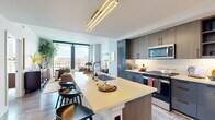 Located in the heart of Midtown Atlanta, this thoughtfully designed one-bedroom, one-bathroom residence offers a refined urban living experience. The open-concept layout seamlessly connects the kitchen, dining, and living areas, creating a bright and cohesive space bathed in natural light from expansive floor-to-ceiling windows that frame striking city skyline views.

The chef-inspired kitchen is a standout feature, showcasing a large waterfall-edge island with bar seating, sleek two-tone cabinetry in warm wood and deep navy, a full suite of stainless steel appliances, and a stylish linear gold pendant light overhead. A stacked in-unit washer and dryer add everyday convenience.

The living room is airy and inviting, with large windows overlooking the Atlanta skyline, hardwood-style flooring, and clean white walls that provide a versatile backdrop. The bedroom continues the floor-to-ceiling window theme, offering sweeping views of the city and a ceiling fan for added comfort. A dedicated closet provides organized storage.

The bathroom features a glass-enclosed walk-in shower, a wood-toned vanity with a white countertop, and elegant tile detailing throughout. Every room reflects a modern design sensibility with high-quality finishes throughout.