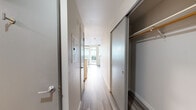 Located on the fifth floor of a contemporary mid-rise building in Seattle's Queen Anne neighborhood, this efficiently designed studio unit offers a well-organized layout across a single level. The building's modern exterior features floor-to-ceiling glass curtain walls and a clean grey paneled facade, reflecting the urban surroundings.

Inside, light wood-tone flooring runs throughout, creating visual continuity. A narrow entry hallway leads past a sliding-door closet with built-in shelving and a hanging rod, providing practical storage. The galley-style kitchen is outfitted with dark wood cabinetry, white upper cabinets, stainless steel appliances including a refrigerator, range, and built-in microwave, as well as a stainless steel undermount sink with a modern faucet and light stone countertops.

The living area is bright and open, benefiting from large windows that bring in natural light and connect the interior to the outdoors. The bathroom features wood-look flooring, a pedestal sink, a large wall mirror with an integrated medicine cabinet, and dark tile accents along the wall.

A private balcony extends the living space outdoors, offering views of the surrounding urban landscape and partial water views of Lake Union, making it a standout feature of this compact yet functional unit.