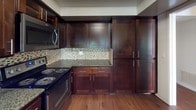 Located at 200 City Blvd W in Orange, California, this single-floor residence offers a well-designed layout with a cohesive blend of modern finishes and functional living spaces. The open living area is anchored by rich, dark hardwood flooring and features a built-in wet bar with a wine rack, dark granite countertops, and a sink — a distinctive architectural detail that adds character to the space. Sliding glass doors lead to a private balcony overlooking lush greenery, allowing natural light to fill the room. Textured ceilings are present throughout.

The kitchen is thoughtfully appointed with dark wood cabinetry, granite countertops, a mosaic tile backsplash, stainless steel appliances including a refrigerator and over-the-range microwave, and an electric range. A breakfast bar connects the kitchen to the main living area, enhancing the open-concept feel.

The bedrooms are carpeted for comfort and each features mirrored sliding closet doors that reflect natural light from nearby windows. The neutral, warm-toned walls create a calm and versatile atmosphere throughout.

The bathrooms are clean and functional, with one featuring a standalone glass-enclosed shower and another offering a shower-tub combination with sliding glass doors and chrome fixtures. Hardwood flooring extends into the bathroom areas, tying the home's design together seamlessly.