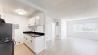 Located at 14350 Vanowen St, Unit 106 in Los Angeles, CA, this one-bedroom, two-bathroom residence offers a thoughtfully designed single-floor layout. Light wood-tone flooring runs throughout, complementing a bright, neutral color palette that gives the space an airy, clean feel.

The open-concept kitchen flows directly into the living area, creating a cohesive and functional shared space. The kitchen is outfitted with white shaker-style cabinetry featuring black hardware, dark granite countertops, a black gas range with overhead ventilation, and a stainless steel sink. A textured ceiling and flush-mount lighting complete the kitchen area.

The living room is generously proportioned, featuring a ceiling fan with integrated lighting, a wall-mounted AC unit, and a large window dressed with vertical blinds that allows natural light to fill the room.

The bedroom offers a comfortable footprint with a mirrored sliding closet, light wood flooring, a textured ceiling, and a window with vertical blinds. Two closets are included across the unit, providing ample storage.

Both bathrooms are finished in crisp white, with one featuring a full tub-shower combination equipped with a dual shower head and chrome fixtures. A hallway connects all rooms, maintaining a practical and organized flow throughout the residence.