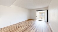 Located at 1515 W Missouri Ave in Phoenix, Arizona, this one-bedroom unit offers a thoughtfully designed, efficient layout across a single floor. The space is finished with warm, variegated luxury vinyl plank flooring that runs throughout, tying each area together cohesively.

The open living room serves as the heart of the unit, bathed in natural light from a sliding glass door that opens onto a private balcony with exterior views — a welcoming feature in the sunny Phoenix climate. A pass-through counter connects the living area to the kitchen, creating an open, communicative feel between the two spaces.

The galley-style kitchen is well-appointed with dark charcoal cabinetry extending to the upper walls, light countertops, a stainless steel sink, and black appliances including a gas range and full-size refrigerator. A ceiling fan overhead keeps the space comfortable.

The bedroom is a generously sized private retreat, featuring a window that admits natural light and connects to a dedicated bathroom with a wall-mounted light fixture and sink vanity. The six-panel dark-trimmed door adds a bold, modern contrast against the crisp white walls.

Throughout the unit, white walls and textured ceilings provide a clean, neutral backdrop, while dark door and cabinet finishes introduce a contemporary design accent that gives the space a fresh, updated character.
