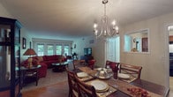 This thoughtfully designed single-floor residence offers a seamless flow between its primary living spaces. The living room serves as a welcoming centerpiece, featuring plush carpeting, a bold sectional sofa, and a set of French doors that fill the room with natural light and provide views of the surrounding greenery. An elegant chandelier illuminates the adjacent dining area, which connects smoothly to the living room and offers ample space for formal entertaining.

A dedicated formal dining room features rich hardwood flooring and its own chandelier, creating an intimate setting well-suited for gatherings. The kitchen is outfitted with warm wood cabinetry, a gas range, dishwasher, and generous counter space, complemented by hardwood-style flooring for easy maintenance.

The primary bedroom is carpeted and comfortably sized, with a window overlooking outdoor greenery and access to a well-appointed bathroom featuring tile wainscoting, a glass-enclosed shower, and a vanity with built-in storage. A spacious walk-in closet provides excellent organization potential. A flexible den with carpet, a large window, and built-in desk area offers additional functionality. The layout overall conveys a sense of ease and comfortable, classic living.