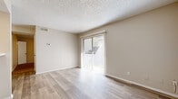 This single-floor residence offers a clean, modern aesthetic throughout its thoughtfully designed layout. The living area is bright and welcoming, featuring light-toned laminate wood flooring that extends across the main living spaces. A full-width sliding glass door fitted with vertical blinds allows abundant natural light to fill the room while providing direct access to an outdoor area, creating a seamless indoor-outdoor connection. A wall-mounted thermostat and ceiling ventilation ensure year-round climate comfort, while the textured popcorn ceiling adds a classic character consistent throughout the home.

The kitchen is a functional and stylish highlight, showcasing white cabinetry with sleek hardware, a marble-patterned countertop with contrasting dark veining, under-cabinet range hood, and a stainless steel range. The raised breakfast bar provides a natural divide between the kitchen and living area.

The bedroom is generously sized, finished with plush wall-to-wall carpeting and neutral beige tones. A large window draws in natural light, and an adjacent walk-in closet offers ample shelved storage space, enhancing the room's practicality. The overall palette of warm beige and white tones throughout the space creates a cohesive, calm, and move-in-ready environment.