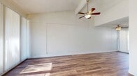 Located at 1125 Pine Ave in Redlands, CA, this two-bedroom, one-bathroom single-story home offers a functional and well-appointed layout across a comfortable footprint. Rich wood-look flooring flows consistently throughout, lending warmth and cohesion to every room.

The living room is a standout space, featuring vaulted ceilings, a ceiling fan with light fixture, and textured ceiling detail. Large sliding glass doors with vertical blinds invite abundant natural light and open to a private patio, seamlessly connecting indoor and outdoor living.

The kitchen is outfitted with white cabinetry, dark granite-style countertops, a stainless steel double sink, and a full-size refrigerator. A window with vertical blinds provides natural light, making the space feel open and functional.

Both bedrooms are bright and well-sized, each featuring ceiling fans, windows with vertical blinds, and wall-unit air conditioning. The primary bedroom offers generous proportions and ample closet access. Three closets are distributed throughout the home, providing excellent storage.

The bathroom features a dark granite vanity with white cabinetry, wood-look flooring, and grab bars for added accessibility. A hallway connects the main areas of the home, completing this practical and inviting single-floor layout.
