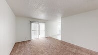 Located at 10316 Blackwood Ave in El Paso, TX, this single-story unit offers a practical and efficiently designed layout across a single floor. The living area features warm beige carpeting and a textured popcorn ceiling, with a sliding glass door fitted with vertical blinds that brings in natural light and provides outdoor access. The space flows into a tiled dining area adjacent to the kitchen, which is brightened by a large window with horizontal blinds. The galley-style kitchen is equipped with gray cabinetry on both sides, tile countertops, a double stainless steel sink, an electric range, and a dishwasher — maximizing functionality within a compact footprint. The generously sized primary bedroom is carpeted and bathed in natural light, with direct access to a bathroom that includes a vanity with mirror and a bathtub. A dedicated walk-in closet off the bedroom features dual hanging rods and tile flooring, offering organized storage. A hallway connects the main areas of the unit. Throughout, the clean white walls and neutral finishes create a bright, cohesive aesthetic well-suited to comfortable everyday living.