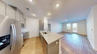 This well-appointed 2-bedroom, 2-bathroom residence at 340 W Third St SW in Rome, GA offers a thoughtfully designed single-floor layout. The open-concept kitchen and living area serves as the heart of the home, anchored by a large granite-topped island with an undermount sink and stainless steel dishwasher. The kitchen is outfitted with gray shaker-style cabinetry, a subway tile backsplash, and a full suite of stainless steel appliances including a refrigerator, range, and microwave. Wood-style flooring flows throughout the main living areas, creating a warm, cohesive aesthetic. Natural light pours in through large windows and a glass balcony door, which opens to a private outdoor space. The bedrooms are carpeted for comfort, each featuring a ceiling fan, ample natural light, and generous closet space — including a well-organized walk-in closet with wire shelving. Both bathrooms mirror the home's refined finishes, with granite vanity tops, gray cabinetry, and brushed gold hardware. A dedicated laundry area and utility room add practical convenience. The clean white walls and recessed lighting throughout lend the space a bright, contemporary feel.