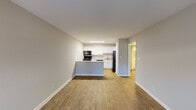 Located on Hunt Club Road in Greensboro, NC, this single-floor unit offers a clean, functional layout with a cohesive neutral color palette throughout. The open-concept living and dining area is finished with warm wood-look flooring and features a front-facing window that draws in natural light, creating a welcoming and airy atmosphere. A paneled entry door anchors the main entrance, adding a classic touch.

The kitchen flows seamlessly from the living area via a peninsula-style counter that provides additional workspace and casual seating potential. Crisp white cabinetry lines the walls, complemented by light granite-style countertops and a full suite of black appliances, including a gas range, over-the-range microwave, dishwasher, and refrigerator. A recessed ceiling fixture provides bright, even illumination throughout the kitchen.

The bedrooms are carpeted for comfort and finished in soft gray tones, with windows fitted with blinds offering natural light and privacy. At least one bedroom includes a walk-in closet with built-in shelving, adding practical storage. The bathroom features a tiled tub-shower combination, a wall-mounted mirror cabinet, and clean white fixtures, keeping the space simple and functional.

Overall, the unit presents a refreshed interior with consistent finishes and a practical, well-organized floor plan.