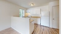 Located at 51 Hampshire Lane in Gibsonia, PA, this single-floor, one-bedroom, one-bathroom unit offers a clean and functional layout with a bright, neutral aesthetic throughout. Light hardwood-style flooring runs continuously across the living areas and bedroom, lending a cohesive and airy feel to the space.

The kitchen is thoughtfully designed with ample white cabinetry extending to the upper walls, warm-toned countertops, and a full suite of white appliances including an electric range and refrigerator. A double-basin sink sits beneath a window that frames views of surrounding greenery, filling the space with natural light. A half-wall peninsula separates the kitchen from the adjoining living area, creating an open yet defined layout.

The bedroom is comfortably sized, featuring a ceiling fan with light fixture, a large closet with bi-fold doors, and a window that allows natural light to filter in. A wall-mounted PTAC unit provides individualized climate control.

The bathroom is neatly appointed with a warm-toned tile floor, a wooden vanity with a single sink, a full tub and shower combination with a curved curtain rod, and clean white wall surrounds. An open shelving nook adjacent to the entry provides convenient storage.

Overall, the unit presents a clean, move-in-ready environment with practical finishes and a welcoming, low-maintenance character.