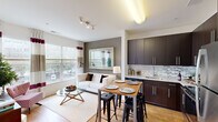 This three-bedroom, two-bathroom residence in Alexandria, Virginia offers a well-designed single-floor layout that maximizes every inch of its space. The open-concept living and dining area is anchored by large windows that flood the room with natural light and offer views of the surrounding streetscape. The kitchen sits adjacent to the living area and features dark espresso cabinetry, a mosaic tile backsplash, light stone countertops, and a sink positioned along the wall — an efficient and stylish layout ideal for everyday living.

The primary bedroom includes a large window framing outdoor views, plush carpeting, and a warm, neutral color palette. The two additional bedrooms offer comfortable proportions, with one showcasing a bold mauve accent wall and another featuring a built-in closet with sliding doors.

Both bathrooms are finished with large-format tile flooring, dark espresso vanity cabinetry, white countertops, and tub-shower combinations with clean white tile surrounds. Warm taupe wall tones create a cohesive, grounded aesthetic throughout the bathrooms.

A connecting hallway ties all rooms together efficiently. Track lighting in the living area and consistent warm-toned walls throughout the residence contribute to a cohesive and inviting overall ambiance.