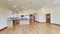 Located at 13569 Bonanza Cir in Cresson, TX, this well-appointed single-story home offers four bedrooms, three bathrooms, and a thoughtfully designed layout. Vaulted ceilings carry throughout the main living areas, creating an open, airy atmosphere complemented by light wood-look flooring and warm wood baseboards. The kitchen and living room share an expansive open-concept space featuring soaring ceilings with recessed lighting, a center island with dark granite countertops, white upper cabinetry, two-tone lower cabinetry, a tile backsplash, and stainless steel appliances. Large windows flood the living area with natural light and provide views of the surrounding neighborhood. The generously sized primary bedroom includes vaulted ceilings and leads to a walk-in closet with built-in shelving and hanging rods. The primary bathroom is highlighted by a dual-sink vanity with dark granite countertops, light wood cabinetry, black hardware, oval mirrors, and a glass-enclosed shower with marble-style tile surround. Secondary bathrooms offer similar quality finishes. Additional bedrooms feature vaulted or angled ceilings, light flooring, and natural light from exterior windows. A dedicated laundry room with washer and dryer hookups, and an attached two-car garage with an automatic opener, complete this home.