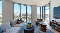 Located at 2801 Sunset Place in Los Angeles, this single-floor residence offers a sophisticated modern design with an emphasis on natural light and urban views. The living area is defined by expansive floor-to-ceiling corner windows framing panoramic views of the Los Angeles skyline, palm-lined streets, and surrounding cityscape. Light wood flooring runs throughout, complementing the clean, neutral palette of the interiors.

The kitchen is outfitted with stainless steel appliances, including a gas range, built-in microwave, and full-sized refrigerator. Light wood cabinetry pairs with white countertops to create a bright, functional workspace that flows into the main living area.

Two bedrooms provide comfortable retreats. One features a bold teal accent wall and large windows, while the second offers a bright, airy feel with a built-in closet and floor-to-ceiling windows overlooking the city. Both rooms are finished with light wood flooring and ample natural light.

Two full bathrooms mirror each other in design, each featuring a soaking tub with overhead shower, light wood vanity cabinetry, white countertops, and illuminated mirrors, delivering a clean, contemporary aesthetic throughout.