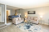 Located on Hollywood Boulevard in Los Angeles, Unit 404 is a thoughtfully designed single-floor residence that blends comfort and functionality in one of the city's most iconic neighborhoods. The open-concept living and dining area serves as the heart of the unit, featuring light wood-style flooring, neutral gray walls, and a textured ceiling throughout. A plush sofa set arranged around a glass-top coffee table anchors the living space, complemented by a Hollywood Sign canvas print that pays homage to the unit's storied surroundings. A ceiling fan with integrated lighting adds both practicality and a casual aesthetic. The dining area sits adjacent to the living room, with direct access to a private balcony that allows natural light to flow freely into the space. The galley-style kitchen is efficiently laid out with white cabinetry, warm-toned countertops, a stainless steel refrigerator, and a double-basin sink, providing ample workspace and storage. The bedroom offers a quiet retreat with generous proportions, soft gray walls, and hardwood-style flooring, with a direct connection to the bathroom. The bathroom features a white vanity with under-cabinet storage, a well-lit mirror, and clean, bright finishes throughout. This unit presents a cohesive, move-in-ready living environment in the heart of Hollywood.