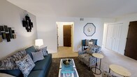This 2-bedroom, 1-bathroom residence is thoughtfully laid out across a single floor, making efficient use of its space to create a comfortable and inviting home. The living room serves as the heart of the unit, featuring soft wall-to-wall carpeting and neutral-toned walls that provide a warm, versatile backdrop for any décor style. The room offers ample space for seating and entertaining, with a welcoming ambiance enhanced by natural light. A hallway connects the living area to the rest of the home, providing easy access to the bedrooms and bathroom. The clean, simple architectural lines throughout the unit give it a timeless, understated character. The open flow between rooms contributes to a sense of spaciousness that makes the home feel larger than its footprint suggests. Neutral tones dominate the interior palette, lending the space a calm and cohesive aesthetic. With its practical single-floor design, this residence is well-suited for a range of lifestyles, offering two private bedrooms ideal for rest or use as a home office, along with a full bathroom to serve the household comfortably.