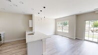 Located at 86 Creek Rd in Poughkeepsie, NY, this thoughtfully designed one-bedroom, one-bathroom unit offers a clean, modern aesthetic across a single level. Light hardwood-style flooring runs throughout, complementing the warm neutral wall tones that lend a bright and airy feel to every room.

The open-concept kitchen and living area serves as the heart of the unit. The kitchen is well-appointed with white cabinetry, stainless steel appliances including a refrigerator, range, and microwave, and a generous quartz countertop peninsula that also functions as a breakfast bar. Stylish pendant lighting hangs above the peninsula, adding a contemporary accent. A dedicated dining area connects seamlessly to the living space, which is bathed in natural light from large windows and a sliding glass door that opens to the outdoors.

The spacious primary bedroom is notably generous in size and features dual closets, providing ample storage. A bright window brings in natural light and outdoor views, enhancing the room's welcoming atmosphere.

The layout also includes an additional room with recessed lighting, offering flexible use as a home office or den. Throughout the unit, recessed lighting, clean white trim, and a cohesive modern design create a polished, move-in-ready living environment.