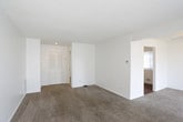 This single-floor residence offers a clean, straightforward layout designed for comfortable everyday living. The spacious living area is finished with neutral wall-to-wall carpeting and features large floor-to-ceiling vertical blinds that allow abundant natural light to fill the room, creating a bright and open atmosphere. A ceiling fan provides additional comfort in the adjoining carpeted room, which connects seamlessly to other areas of the home via an open passage.

The bedrooms are carpeted and bathed in natural light through well-positioned windows, offering a quiet and airy feel. Each room features clean white walls and ample floor space, providing a versatile canvas for a variety of furnishing arrangements.

The kitchen is equipped with white cabinetry, light countertops, a stainless steel sink, a white dishwasher, and a black electric range with a ventilation hood. A white tile backsplash adds a clean, classic touch, while the dark hardwood-style flooring grounds the space with warmth and contrast.

The full bathroom includes a single-sink vanity with white cabinetry and a wood-framed mirror, a toilet, and a tiled tub and shower combination. The warm-toned stone-look tile flooring adds texture and durability to the space. Overall, the residence presents a functional and well-organized layout with consistent, neutral finishes throughout.