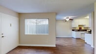 This single-floor, 2-bedroom, 1-bathroom residence offers a practical and comfortable layout designed to maximize everyday living. The open living area features warm wood-look flooring, a textured ceiling, and a large window fitted with vertical blinds that allows natural light to fill the space. A ceiling fan with a light fixture adds both style and functionality to the room.

The galley-style kitchen is efficiently designed with white cabinetry extending to the ceiling, dark granite-style countertops, wood-look flooring, and black appliances including a range and refrigerator, providing ample storage and workspace.

Both bedrooms are carpeted and include ceiling fans, vertical-blind windows, and neutral beige walls, creating a calm and restful atmosphere. The primary bedroom offers a comfortable amount of space, while a dedicated closet with built-in shelving and hanging rods provides convenient storage.

The full bathroom features a double-sink vanity with dark countertops and white cabinetry, a large wall mirror, wood-look flooring, and a tiled shower-tub combination, offering a clean and functional design.

A hallway connects the main living areas to the bedrooms and bathroom, ensuring a logical and efficient flow throughout the home. The consistent use of neutral tones and cohesive finishes gives the entire residence a unified, well-maintained appearance.
