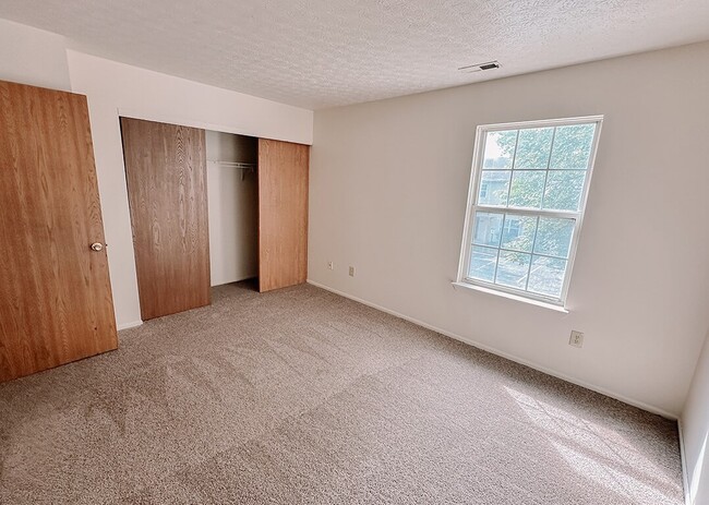 Dormitorio con ventana y armario - Madison Grove Townhomes