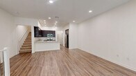 Located at 560 Winchester in Oxnard, CA, this contemporary multi-story home spans three floors and offers a well-organized layout with 2 bedrooms and 3 bathrooms. The entry level provides a welcoming foyer that leads upstairs to the main living floor. The heart of the home is an open-concept kitchen and living area featuring rich dark-espresso cabinetry, light granite countertops, stainless steel appliances including a gas range and built-in microwave, and a peninsula with a stainless steel sink — ideal for cooking and entertaining. Wide-plank wood-style flooring runs throughout the main living areas, complemented by recessed lighting and crisp white walls that create a bright, clean aesthetic. Large windows in the living area invite natural light and provide outdoor views. The upper floor hosts both bedrooms, each carpeted for comfort. The spacious primary bedroom includes direct access to a private en-suite bathroom with a walk-in glass shower, white quartz vanity, and dark cabinetry. A second full bathroom features a tiled tub-shower combo with chrome fixtures. White balustrade staircases with wood-tone treads connect all three levels, adding a clean architectural detail throughout the home.