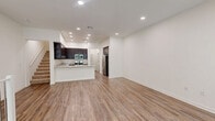 Located at 560 Winchester in Oxnard, CA, this contemporary multi-story home spans three floors and offers a well-organized layout with 2 bedrooms and 3 bathrooms. The entry level provides a welcoming foyer that leads upstairs to the main living floor. The heart of the home is an open-concept kitchen and living area featuring rich dark-espresso cabinetry, light granite countertops, stainless steel appliances including a gas range and built-in microwave, and a peninsula with a stainless steel sink — ideal for cooking and entertaining. Wide-plank wood-style flooring runs throughout the main living areas, complemented by recessed lighting and crisp white walls that create a bright, clean aesthetic. Large windows in the living area invite natural light and provide outdoor views. The upper floor hosts both bedrooms, each carpeted for comfort. The spacious primary bedroom includes direct access to a private en-suite bathroom with a walk-in glass shower, white quartz vanity, and dark cabinetry. A second full bathroom features a tiled tub-shower combo with chrome fixtures. White balustrade staircases with wood-tone treads connect all three levels, adding a clean architectural detail throughout the home.