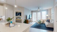 Located at 2991 Gulf to Bay Blvd in Clearwater, Florida, this thoughtfully designed single-floor residence offers a bright, open-concept layout with a cohesive modern aesthetic throughout. The kitchen serves as a central highlight, featuring crisp white shaker cabinetry, a subway tile backsplash, stainless steel appliances, under-cabinet lighting, and a generous island with quartz countertops illuminated by globe pendant lights — ideal for both cooking and casual dining with bar seating. Light wood-tone flooring flows seamlessly into the living area, which is bathed in natural light from large French doors and windows dressed with sheer curtains. A ceiling fan adds comfort, while the open sightlines create an airy, welcoming atmosphere. The primary bedroom offers plush carpeting, generous natural light from large windows with elegant drapery, and direct access to a spacious en-suite bathroom featuring a dual-sink vanity with white cabinetry, quartz countertops, framed mirrors, pendant lighting, and open shelving for added storage. A second bedroom provides comfortable accommodations, while a second full bathroom mirrors the polished design of the primary bath. The overall ambiance is clean, coastal-inspired, and move-in ready.