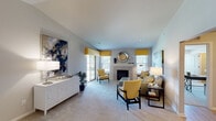 This two-floor residence offers a well-organized layout with distinct living, dining, and sleeping areas connected by a consistent neutral color palette and warm design details throughout. The living room serves as a central gathering space, anchored by a tile-surround fireplace flanked by windows dressed in yellow roman shades that invite natural light. Plush carpeting, a sliding glass door to an outdoor area, and generous wall space for artwork contribute to the room's comfortable and stylish atmosphere.

Adjacent to the living room, the dining area accommodates a round table beneath a pendant light fixture, with direct access to the kitchen. The kitchen features white shaker-style cabinetry, granite countertops, light hardwood-style flooring, and stainless steel appliances, providing a functional and clean workspace.

The bedrooms are carpeted and designed with practicality in mind, each offering ample storage and access to closets. The bathroom presents granite countertops on white vanity cabinetry, tile flooring, a tiled shower enclosure, and a window providing natural ventilation. Overall, the residence maintains a cohesive, contemporary aesthetic across both floors.
