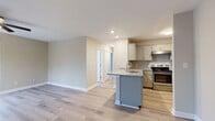 Located at 415 W 10th Street in the heart of Charlotte, NC, this single-floor residence offers a thoughtfully designed layout with modern finishes throughout. Light wood flooring flows seamlessly across all rooms, creating a cohesive and airy aesthetic.

The kitchen serves as a functional centerpiece, featuring granite countertops, a peninsula with an integrated sink, white cabinetry, and a full suite of stainless steel appliances including a range, refrigerator, and microwave. The open layout connects the kitchen directly to the living area, promoting an easy flow between spaces.

A standout feature is the curved bay window area, where a series of large windows flood the space with natural light and provide views of the surrounding neighborhood's tree-lined scenery. Ceiling fans are installed throughout the bedrooms and living areas, enhancing comfort year-round.

The bedrooms are generously proportioned, each with multiple windows that allow ample natural light. The primary bedroom includes direct access to a private en-suite bathroom as well as a walk-in closet. Warm neutral wall tones complement the light flooring throughout, contributing to a calm and inviting atmosphere. Clean white trim and baseboards add a crisp finishing touch to each room, making this a well-appointed and move-in-ready space.