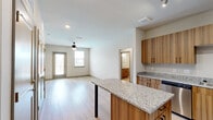 Located at Chatham Center Drive in Savannah, Georgia, this single-story, three-bedroom, one-bathroom residence offers a thoughtfully designed open floor plan with contemporary finishes throughout. The combined kitchen and living area serves as the heart of the home, where light wood-tone cabinetry, granite countertops, and a central island with bar-height seating define the kitchen space. Stainless steel appliances—including a refrigerator, range, microwave, and dishwasher—complement the modern aesthetic. Light hardwood-style flooring extends throughout the main living areas, enhancing the bright, airy ambiance created by natural light from large windows and a glass-panel exterior door. A ceiling fan overhead adds to the comfortable atmosphere of the living room. The three bedrooms offer ceiling fans and windows with blinds; two feature soft carpeting, while one showcases the same hardwood-style flooring as the main living area. The primary bedroom connects to a well-organized closet equipped with wire shelving and hanging rods, alongside a vanity with matching granite countertop. A dedicated walk-in closet with extensive wire shelving provides additional storage throughout the unit.