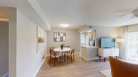 This thoughtfully designed single-floor residence offers a cohesive open-concept layout that connects the living, dining, and kitchen areas seamlessly. The living room is bright and welcoming, featuring light wood-style flooring, a ceiling fan, and large sliding glass doors that open to a private balcony with lush outdoor views — an ideal setting for relaxing or entertaining. Adjacent to the living area, the dedicated dining space accommodates a round table with ease, framed by contemporary wall art that adds character to the neutral-toned walls.

The kitchen is clean and functional, outfitted with crisp white cabinetry, quartz countertops, a classic subway tile backsplash, a stainless steel sink, and a window that brings in natural light. A pass-through counter connects the kitchen to the dining area, enhancing the open feel of the shared living spaces.

The residence includes two well-proportioned bedrooms, both finished with plush carpeting. Each bedroom features a closet and windows that allow natural light to filter in. The two bathrooms are finished with white vanities, large mirrors, and clean, modern fixtures — one featuring a shower/tub combination. Light wood-style flooring carries through the main living areas, tying the entire space together with a warm, contemporary aesthetic.