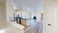 Located at 219 Adams Pointe Blvd N in Mars, PA, this well-appointed one-bedroom, one-bathroom home offers a thoughtfully designed single-floor layout. The open-concept living and kitchen area serves as the heart of the home, anchored by light wood-look flooring that flows seamlessly throughout the main living spaces. The kitchen is outfitted with cream-toned cabinetry featuring detailed crown molding, striking dark granite countertops, stainless steel appliances, and a central island with a built-in sink — ideal for both cooking and casual dining. The kitchen opens directly into the bright living room, which features crown molding, a ceiling fan, and a classic fireplace with a dark granite surround and white mantle. Multiple windows invite abundant natural light and offer views of the surrounding autumn foliage. The generously sized bedroom is finished with plush carpet, crown molding, a ceiling fan, and a large window framing colorful outdoor views. A dedicated closet provides ample storage. The full bathroom is clean and modern, featuring large-format white tile flooring, a dark granite vanity, white cabinetry, and a glass-door tub-shower combination. A utility room completes the functional layout of this comfortable home.