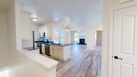 Located at 219 Adams Pointe Blvd N in Mars, PA, this well-appointed one-bedroom, one-bathroom home offers a thoughtfully designed single-floor layout. The open-concept living and kitchen area serves as the heart of the home, anchored by light wood-look flooring that flows seamlessly throughout the main living spaces. The kitchen is outfitted with cream-toned cabinetry featuring detailed crown molding, striking dark granite countertops, stainless steel appliances, and a central island with a built-in sink — ideal for both cooking and casual dining. The kitchen opens directly into the bright living room, which features crown molding, a ceiling fan, and a classic fireplace with a dark granite surround and white mantle. Multiple windows invite abundant natural light and offer views of the surrounding autumn foliage. The generously sized bedroom is finished with plush carpet, crown molding, a ceiling fan, and a large window framing colorful outdoor views. A dedicated closet provides ample storage. The full bathroom is clean and modern, featuring large-format white tile flooring, a dark granite vanity, white cabinetry, and a glass-door tub-shower combination. A utility room completes the functional layout of this comfortable home.