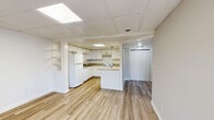 Located at 1055 Hickory Hill Ln in Nashville, TN, this one-bedroom, one-bathroom unit offers a practical and well-organized single-floor layout. The kitchen is a standout feature, boasting abundant white cabinetry that extends to the ceiling for generous storage, granite-look countertops, a double sink, a white electric range, a refrigerator, and a peninsula that adds additional prep and serving space. Light wood-look flooring runs throughout the kitchen and main living areas, creating a clean, cohesive look. The bedroom is a comfortable, carpet-floored retreat featuring a double sliding-door closet, neutral wall tones, a drop ceiling with a flush-mount light fixture, and a window that allows natural light to filter in. The bathroom is finished in an all-white palette, complete with a tub/shower surround, a vanity with under-sink storage, a wall-mounted cabinet for additional organization, and matching wood-look flooring that ties it to the rest of the unit. A hallway connects the rooms efficiently, contributing to the unit's smart use of space. The overall design is clean and functional, with a neutral color scheme throughout.