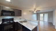 Located at 3002 Kingston Cir in Greenville, NC, this single-floor residence offers a well-designed open-concept layout that connects the kitchen and living areas seamlessly. The kitchen is a standout feature, equipped with dark espresso cabinetry, striking marble-look countertops, a stainless steel sink, and a full suite of black appliances including a refrigerator, electric range, built-in microwave, and dishwasher. A breakfast bar provides additional counter space and a natural transition into the living area.

The living room is bright and welcoming, highlighted by a ceiling fan with light fixture, light hardwood-style flooring, and a sliding glass door that opens onto a private balcony with outdoor views of surrounding greenery. The bedrooms feature the same durable hardwood-style flooring, neutral toned walls, and windows with blinds that allow for natural light. One bedroom benefits from access to a dedicated closet and an adjoining bathroom.

The bathroom is clean and functional, featuring a full soaking tub and shower combo with chrome fixtures, wood-look flooring, and a crisp white finish throughout. Textured ceilings are present throughout the unit, adding a classic residential character. Overall, the space presents a practical and comfortable living environment with updated finishes and a cohesive neutral palette.