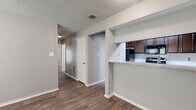 Located at 14900 Nacogdoches Rd in San Antonio, TX, this single-floor, three-bedroom, one-bathroom home offers a practical and well-organized layout throughout. Wood-look flooring runs consistently across the living areas, bedrooms, kitchen, and bathroom, lending a cohesive and clean aesthetic to the entire space.

The kitchen is a standout feature, designed in a U-shaped configuration with rich dark brown cabinetry offering ample storage, light granite countertops, a stainless steel sink, and black appliances including a range and refrigerator. A pass-through counter opens the kitchen toward the main living area, creating an open and connected feel.

The primary bedroom is generously sized and includes a ceiling fan, a walk-in closet with built-in shelving on multiple walls, and an additional closet for extra storage. The secondary bedrooms are also well-proportioned, each featuring ceiling fans and access to natural light through windows with blinds.

The full bathroom is outfitted with a tub-shower combination featuring white tile surround, a granite-topped vanity with dark cabinetry, and a large mirror. A dedicated laundry area with utility connections and an electrical panel provides added convenience. Textured ceilings are present throughout, and the overall layout, as seen in the dollhouse view, is efficient and functional.
