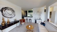 This single-floor residence offers a thoughtfully designed layout with a seamless flow between its main living spaces. The living room is a bright, welcoming area finished with plush carpeting, crown molding, and a sliding glass door that opens to a private balcony overlooking lush greenery. The open-concept kitchen features white cabinetry, dark countertops, and a breakfast bar with stool seating, connecting naturally to the living space. Adjacent to the kitchen, a dedicated laundry room houses a full-size washer and dryer for added convenience.

The dining room makes a bold statement with deep teal accent walls, crown molding, a pendant light fixture, and a window that frames verdant outdoor views. Two well-sized bedrooms provide comfortable retreats, each with plush carpeting and generous natural light. The primary bedroom includes access to a walk-in closet and an en-suite bathroom featuring a dual-sink vanity with white cabinetry. A second full bathroom offers a single-sink vanity with ample counter space and a shower-tub combination. Throughout, the residence maintains a cohesive, contemporary aesthetic with neutral tones and thoughtful design details.