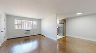 Located at 130 New Rd in Parsippany, NJ, this one-bedroom, one-bathroom residence offers a thoughtfully designed single-floor layout with a warm, updated aesthetic throughout. Rich hardwood flooring flows continuously across the living room, hallway, and bedroom, adding character and cohesion to the space.

The open living room is bright and welcoming, featuring a window that brings in natural light and views of the surrounding neighborhood. A partial wall separates the living area from the kitchen, creating a semi-open feel while maintaining distinct zones. The kitchen has been renovated with white upper cabinetry, warm wood-toned lower cabinets, white quartz countertops, a classic subway tile backsplash, and stainless steel appliances including a dishwasher and refrigerator. Large-format tile flooring and a window above the sink complete the clean, modern look.

The spacious primary bedroom features two double-door closets, providing generous storage, and continues the hardwood flooring found throughout the unit. The bathroom is strikingly modern, featuring large-format white tile, a soaking tub with a glass panel enclosure, chevron mosaic tile accents, a wood-toned vanity with white countertop, and sleek matte black fixtures throughout.