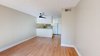 Located at 1628 Bell St in Arcade, California, this single-floor unit offers a clean, functional layout with a bright and neutral aesthetic throughout. The open-concept living area is finished with warm hardwood-style flooring and features a ceiling fan with light fixture, a textured ceiling, and a large window fitted with vertical blinds that allows generous natural light to fill the space. The living area flows seamlessly toward the kitchen, which is designed around a peninsula counter with a grey laminate surface, providing both workspace and a casual bar-style dining option. The kitchen is equipped with white cabinetry extending to the ceiling for ample storage, a white electric range, a full-size refrigerator, a dishwasher, and a stainless steel sink. Additional rooms include carpeted bedroom spaces, each featuring large windows with vertical blinds that invite natural light and outdoor views. The bathroom is outfitted with a full tub and shower combination with tiled surround, a toilet, vanity with storage, and hardwood-style flooring. Neutral beige tones are consistent throughout all rooms, contributing to a calm and cohesive ambiance. The unit is situated on a single floor, offering convenient, accessible living in a well-maintained setting.