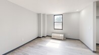 Located at 1930 Marion St in Columbia, SC, this one-bedroom, one-bathroom unit offers a clean, modern design across a single floor. The open living area features light wood-look luxury vinyl flooring, crisp white walls with dark baseboards, and a large black-framed window that brings in natural light and outdoor views. A wall-mounted PTAC unit provides individual climate control. The kitchen is efficiently integrated into the living space, equipped with warm wood-toned cabinetry, a stainless steel oven, a built-in microwave, a dishwasher, and a single-basin sink — all neatly arranged along one wall. The bedroom is a well-proportioned, private retreat with its own black-framed window, a baseboard heating unit, and recessed lighting. A dedicated closet area off the bedroom features built-in shelving and a hanging rod for organized storage. The bathroom is finished with neutral tile flooring, a white vanity with cabinet storage and a mirrored medicine cabinet, a standard toilet, and a shower/tub combination. Throughout the unit, the design emphasizes clean lines, neutral tones, and functional efficiency, making it a practical and comfortable living space.