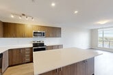 Located at 52 Baker St in Guelph, Ontario, this thoughtfully designed 2-bedroom, 2-bathroom unit offers a well-organized single-floor layout with a clean, contemporary aesthetic throughout. Light-toned luxury vinyl plank flooring flows seamlessly across the space, complemented by crisp white walls and modern trim work.

The open-concept kitchen and living area serves as the heart of the unit. The kitchen is appointed with rich walnut-toned cabinetry, a full suite of stainless steel appliances including a French door refrigerator, electric range, built-in microwave, and dishwasher, as well as a spacious central island with a bright white quartz countertop — ideal for meal preparation and casual dining. Recessed and track lighting illuminates the space effectively.

The living area connects directly to a private balcony through a glass-panelled door, offering elevated views of the surrounding Guelph cityscape and tree canopy. Large windows in the bedrooms also capture plentiful natural light and outdoor views. The primary bedroom provides a comfortable and well-proportioned retreat.

Both bathrooms are finished to a modern standard, with one featuring marble-style tiled walls, a glass-enclosed shower, wood-toned vanity cabinetry, and white quartz countertops. A dedicated den adds flexible living or workspace options. Three hallways, a closet, and in-suite laundry round out the practical and functional layout of this well-appointed Guelph residence.