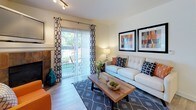 This thoughtfully designed single-floor residence offers a cohesive layout that balances comfort and functionality throughout its key living spaces. The living room serves as the heart of the home, highlighted by a tile-surround fireplace, wood-look flooring, track lighting, and a sliding glass door that opens to an outdoor patio framed by lush greenery — allowing natural light to pour in and creating a seamless indoor-outdoor connection. The galley-style kitchen is lined with ample upper and lower cabinetry with light wood trim, generous counter space, and full appliances, keeping the workspace efficient and organized. Adjacent to the kitchen, the dining area accommodates a full-size dining table and benefits from natural light streaming through a large window, with a ceiling fan overhead adding to its comfort. Two well-proportioned bedrooms feature plush carpeting, natural light from windows with blinds and curtains, and soft wall sconce lighting, lending each room a calm and restful ambiance. A versatile additional room is set up as a home office, complete with carpet flooring and a bright window. The bathrooms include a full tub-and-shower combination with clean white surrounds, and a second bathroom with a walk-in shower. Wood-look flooring flows through the main living areas, tying the space together with a warm, contemporary feel.