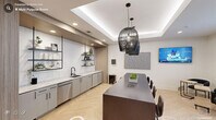 Located at 3500 Louis Stephens Dr in Durham, NC, this thoughtfully designed single-floor gathering space blends modern aesthetics with functional versatility. The open layout is anchored by a large dark-wood communal dining table, illuminated by a trio of striking black wire pendant lights that hang from a coffered ceiling with elegant ambient cove lighting. A herringbone-patterned light wood floor runs throughout, adding warmth and visual continuity to the entire space.

The kitchenette area along one wall features sleek gray cabinetry, marble-look countertops, a stainless steel sink and dishwasher, and open black metal shelving—ideal for catering or casual refreshment service. Adjacent to the main dining area, a lounge zone offers flexible seating arrangements, including a built-in banquette set against a bold textured accent wall, paired with pedestal tables and mixed modern chairs. Curated artwork and a round mirror add personality to the walls, while sheer white curtains frame the windows and invite natural light.

A mounted flat-screen television and integrated power access at the dining table support both social and professional gatherings. A shuffleboard table along the back wall introduces a recreational element, making this space equally suited for team building or casual events. Clean white walls and recessed lighting complete the refined, welcoming ambiance.