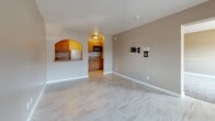 Located at 13031 Central Ave NE in Albuquerque, NM, this well-appointed one-bedroom, one-bathroom unit offers a practical and comfortable layout across a single floor. The living area features light-toned tile flooring that runs throughout, neutral warm-beige walls, and a large sliding window that allows natural light to fill the room. A wall-mounted TV bracket and a window AC unit are included features of the main living space.

The kitchen is accessed through a charming arched pass-through window and a separate entry, and is outfitted with warm wood cabinetry, a built-in microwave, and a refrigerator, making efficient use of the available space.

The generously sized primary bedroom is carpeted for comfort and includes a spacious open closet with a double hanging rod. A sliding glass door opens to a private balcony offering views of the surrounding mountains — a standout feature of the room. The bedroom also connects to the bathroom, which is finished with porcelain tile floors and a tub-shower combination featuring floor-to-ceiling stone-look tile surround.

Overall, the unit presents a clean, functional design with a neutral color palette, practical finishes, and outdoor access — well-suited for comfortable everyday living in the heart of Albuquerque.