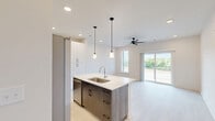 Located in Toccoa, GA, this thoughtfully designed one-bedroom, one-bathroom unit offers a clean, modern aesthetic throughout its efficiently utilized single floor. Light-toned luxury vinyl plank flooring runs throughout, providing a cohesive and low-maintenance foundation for the space.

The kitchen is a standout feature, boasting a large center island topped with striking veined quartz countertops and an undermount sink. Two-tone cabinetry pairs crisp white upper cabinets with dark wood lower cabinets, complemented by stainless steel appliances including a French door refrigerator, range, and over-the-range microwave. Pendant lighting and recessed fixtures illuminate the space effectively.

The bedroom offers a comfortable, light-filled retreat with a ceiling fan and large sliding glass doors that open to an outdoor deck, providing serene views of the surrounding green landscape. The room also provides direct access to the bathroom and a dedicated closet.

The bathroom features a clean, contemporary design with a subway-tiled tub/shower combination, a dark-framed curved shower rod, a wood-toned vanity with white countertop, and light flooring that maintains the home's bright, unified palette.

A hallway connects the rooms efficiently, completing this well-appointed and move-in-ready unit.