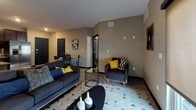 This thoughtfully designed single-floor residence offers a cohesive blend of modern finishes and functional living spaces. The kitchen serves as a centerpiece of the home, featuring rich dark espresso cabinetry, granite countertops, a breakfast bar peninsula, and a full suite of stainless steel appliances including a range, built-in microwave, dishwasher, and French door refrigerator. Light wood-style flooring flows throughout the main living areas, complementing the warm, neutral wall tones. The open-concept living room is generously sized, bathed in natural light from large windows with roller shades, and connects seamlessly to a dining area. The primary bedroom is a comfortable retreat with plush carpeting and direct access to a well-equipped bathroom featuring granite countertops, dark cabinetry, and a spacious walk-in closet with built-in wire shelving. A second bedroom also offers carpeted flooring, a window with natural light, and ample room for furnishings. A versatile flex room provides an ideal space for a home office or study, complete with carpeting and a window. Bathrooms throughout the residence echo the same high-quality finishes, including granite vanity tops and dark wood cabinetry. The overall design balances contemporary style with practical comfort.