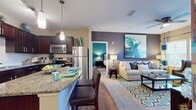 This contemporary apartment in Ooltewah's Royal On Preserve offers 940 square feet of expertly designed living space. The open-concept floor plan seamlessly integrates the kitchen, living, and dining areas, creating a spacious feel. The gourmet kitchen boasts dark wood cabinetry, stainless steel appliances, and granite countertops, complemented by a convenient breakfast bar.

The living room features large windows that flood the space with natural light, while a striking blue abstract artwork serves as a focal point. Plush seating and a geometric area rug add comfort and style. The primary bedroom, measuring 180 square feet, is a tranquil retreat with soothing decor and ample closet space.

Three well-appointed bathrooms showcase modern fixtures, including a glass-enclosed shower. The apartment also includes a dedicated laundry area with full-size washer and dryer. Throughout the home, a cohesive color palette of blues, teals, and neutrals creates a harmonious and inviting atmosphere. Attention to detail is evident in the carefully curated accessories and artwork that adorn each room, making this apartment a true gem in the Ooltewah area.