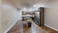 Located at 221 Trowbridge St in Grand Rapids, MI, this 2-bedroom, 2-bathroom unit offers a well-designed, single-floor layout with a thoughtful mix of comfort and functionality. The open-concept living area seamlessly connects the kitchen, dining, and living spaces, creating an inviting and versatile environment. The kitchen is a standout feature, boasting rich dark wood cabinetry, dark granite countertops, a subway tile backsplash, a center island with pendant lighting, and a full suite of stainless steel appliances including a refrigerator, range, microwave, and dishwasher. Wood-style plank flooring runs throughout the main living areas, adding warmth and continuity to the space. A hallway connects the living area to the two bedrooms, each offering natural light through blinds-equipped windows. The bedrooms are carpeted for added comfort, and both include closets, with one featuring a walk-in closet. Three closets in total provide ample storage throughout the unit. The two bathrooms are finished with wood-toned vanities, white countertops, and tile flooring. One bathroom includes a tub/shower combination. Neutral wall tones and clean white trim complete the polished, move-in-ready aesthetic of this Grand Rapids residence.