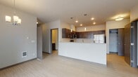 Located at 17016 East Indiana Parkway in Spokane Valley, Washington, this single-floor unit offers a thoughtfully designed open-concept layout that seamlessly connects the kitchen, dining, and living areas. The kitchen is a standout feature, showcasing dark espresso cabinetry with sleek hardware, granite-style countertops, a classic white subway tile backsplash, and a full suite of stainless steel appliances including a refrigerator, electric range, and microwave. A peninsula with an undermount sink provides additional workspace and casual seating, while pendant lighting adds a refined touch overhead. Light wood-look flooring extends throughout the main living areas, creating a clean and cohesive aesthetic. The open living and dining area is bathed in natural light from large windows and a sliding glass door that leads to an outdoor space, complemented by a chandelier in the dining nook. The bedroom features plush carpeting, a window overlooking the surrounding community, and a built-in closet with wire shelving. The bathroom is finished with a dark vanity, granite-style countertop, subway tile accents, a soaking tub, and light flooring that ties the space together. A convenient closet near the main living area offers additional storage.